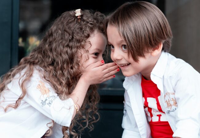 A little girl whispering the best SaaS explainer video secrets into a little boy’s ear